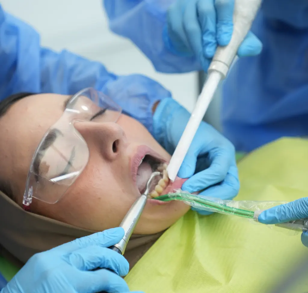 Dentist using airflow cleaning method to remove stains and deposits from the patient's teeth