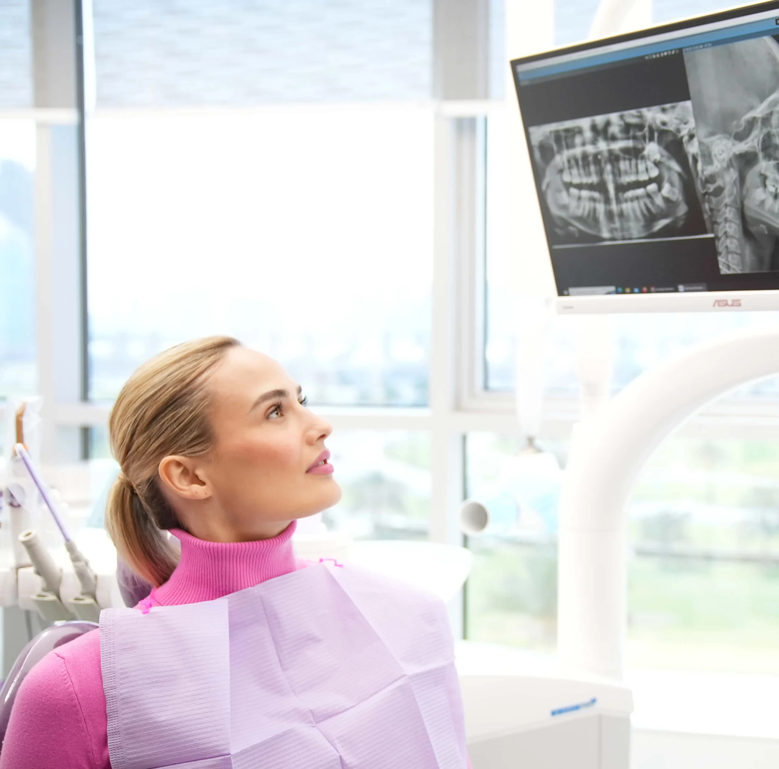 Patient observing her dental X-ray on the screen while the dentist discusses a misaligned tooth.